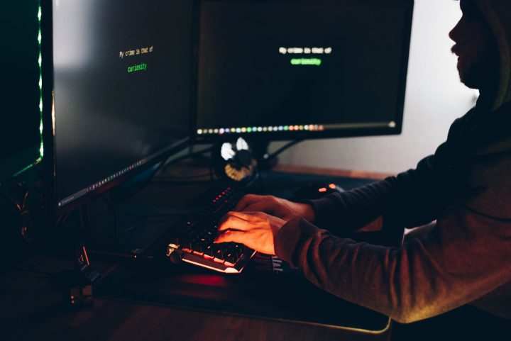 crop hacker silhouette typing on computer keyboard while hacking system phishing attack